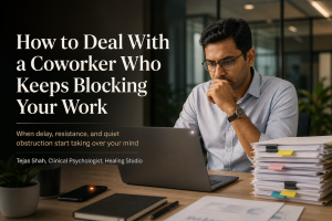 Indian office professional reflecting on how to deal with a coworker who blocks your work in a tense but realistic workplace setting