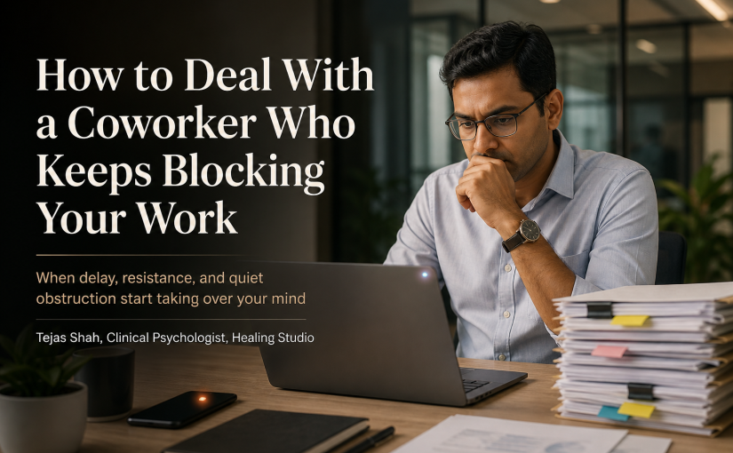 Indian office professional reflecting on how to deal with a coworker who blocks your work in a tense but realistic workplace setting