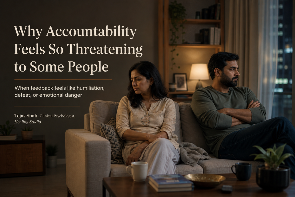 When accountability feels threatening? Indian couple in a tense quiet moment after feedback conversation, illustrating defensiveness and fear of accountability — Tejas Shah | Healing Studio