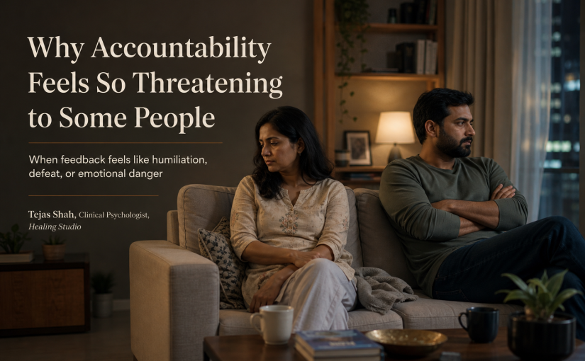 When accountability feels threatening? Indian couple in a tense quiet moment after feedback conversation, illustrating defensiveness and fear of accountability — Tejas Shah | Healing Studio
